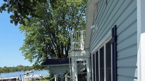 A wooden deck with a view of a lake and a house with a covered staircase.