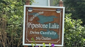 A welcome sign for Pipestone Lake with a cautionary message about driving carefully and no outlet.