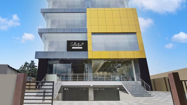 A multi-story building with a glass facade, a yellow section on the right, and a sign reading 'Collection.' - Deluxe Cloud Stay (Guwahati)