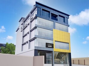 A modern building with a glass facade, a sign reading 'Collection,' and a yellow accent wall. - Deluxe Cloud Stay (Guwahati)