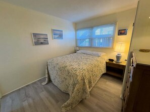 Ein Schlafzimmer mit einem Bett, einem Nachttisch, einer Lampe und zwei gerahmten Bildern an der Wand.