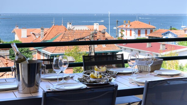 Taula preparada per dinar amb vista al mar i edificis al fons.