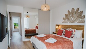 Habitació d'hotel moderna amb un llit gran, un mirall, un panell de fusta al capçal i una obra d'art a la paret.