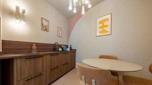 A modern kitchen with wooden cabinets, a round dining table, and two chairs. - Luxury designer suites just a short walk from the Spanish Steps (Roma)