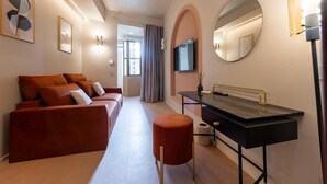 A modern hotel room with a sofa, a round mirror, a TV, and a desk with a lamp. - Luxury designer suites just a short walk from the Spanish Steps (Roma)
