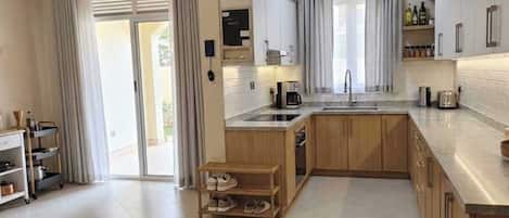 A modern kitchen with a central island, wooden cabinets, and a sliding glass door leading to a balcony.