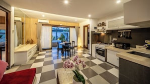 Una cuina moderna amb un paviment a escacs, una zona de menjador amb taula i cadires, i vista a un espai exterior a través d'una porta de vidre.