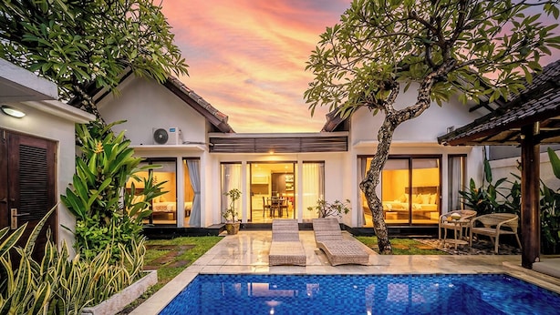 Una casa moderna amb piscina, mobiliari exterior i un gran arbre.