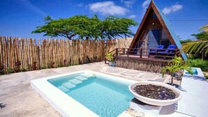 A wooden A-frame structure with a pool and lounge chairs.