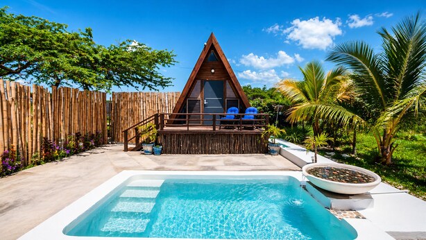 A triangular A-frame building with a pool and lounge chairs.
