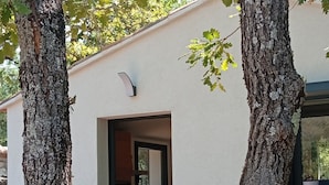 A modern building with a white exterior, a door leading to a kitchen area, and two trees framing the entrance. - A little slice of paradise, nestled in the woods (Ste Baume, Canal de Provence, ... (Rougiers)