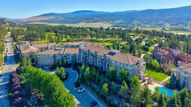 Un hotel de varios pisos con un patio central, rodeado de vegetación y con montañas al fondo.