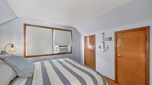 Un dormitorio con cama, ventana, radiador y puerta.