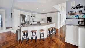 Una cocina moderna con armarios blancos, encimera de granito y espacio para café.
