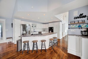 A modern kitchen with white cabinetry, a granite countertop, and a coffee station. - Lake Front Home, Huge fun dock & Hot Tub! (Sunrise Beach)