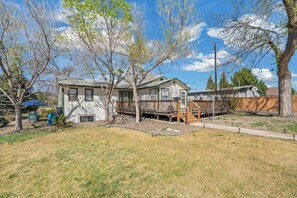 A residential property with a detached house, a wooden deck, and a fenced yard.