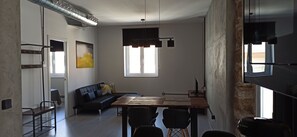 A modern living room with a sofa, dining table, chairs, a TV, and a large window. - Apartment Viña 1 (cadiz)