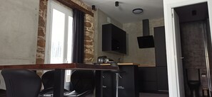 A modern kitchen with a built-in stove, a black countertop, and a wooden dining table with black chairs. - Apartment Viña 1 (cadiz)