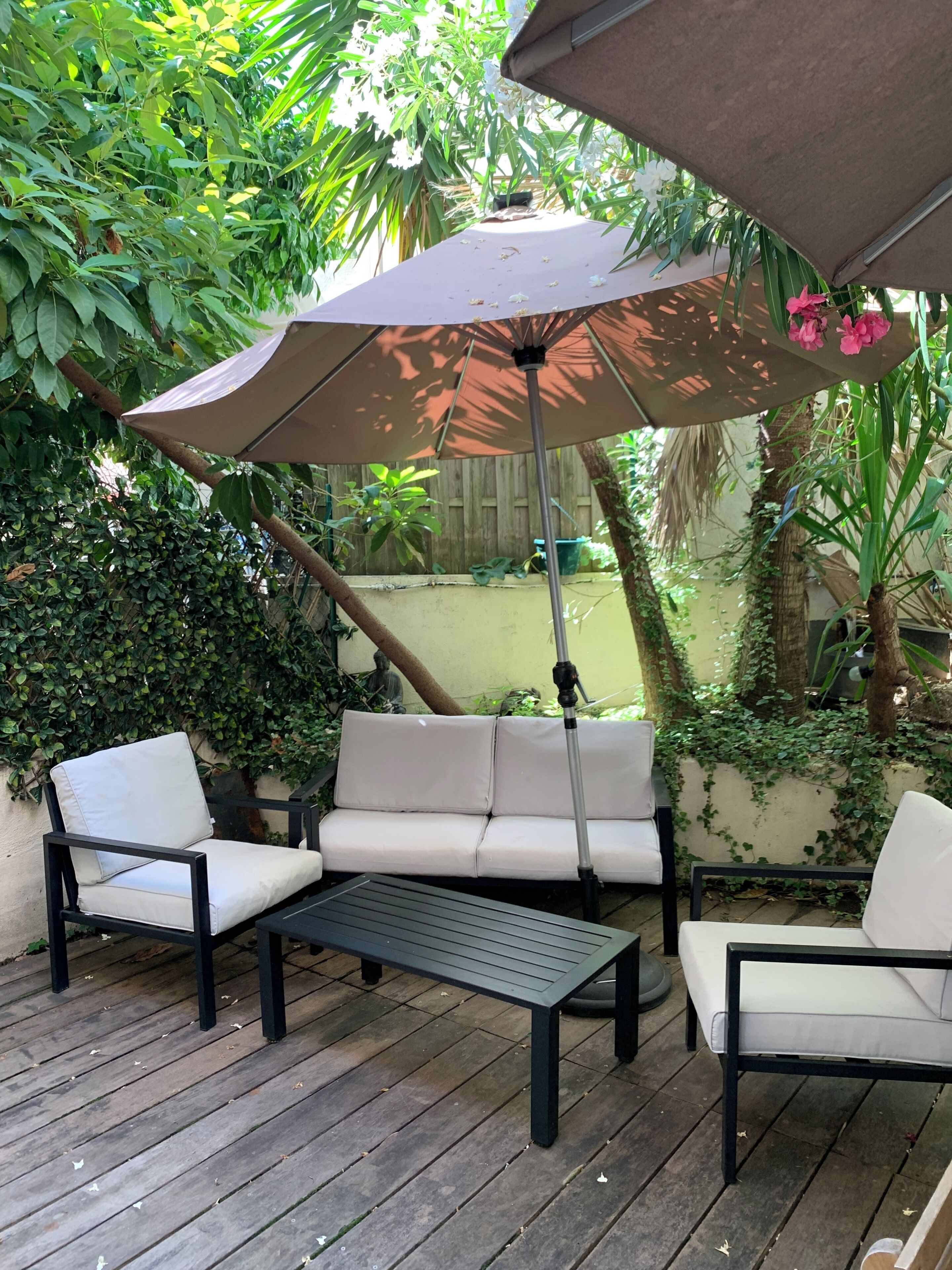 A patio with a sofa, chairs, a table, and an umbrella.