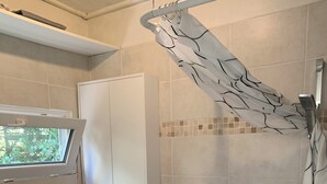 Et badeværelse med toilet, håndvask, badeforhæng og et vindue.
