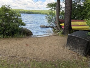 Blick auf einen See mit Steg, Bäumen und einer überdachten Sitzgelegenheit.