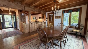 A wooden interior with a dining table, chairs, a chandelier, and a view through a window. - Wine'd Down on Lake Waukewan- New Lisiting- Photos Updated (Meredith)