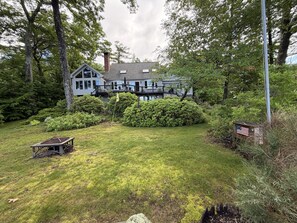 Ein zweistöckiges Haus mit Terrasse, umgeben von üppigem Grün und einem gepflegten Rasen.