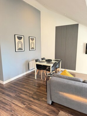 A modern living room with a dining area, wooden flooring, and a gray sofa. - Modern apartment in the centre of Liverpool (Liverpool)