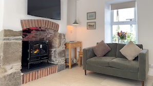 A living room with a fireplace, a sofa, a television, and a window with a view.