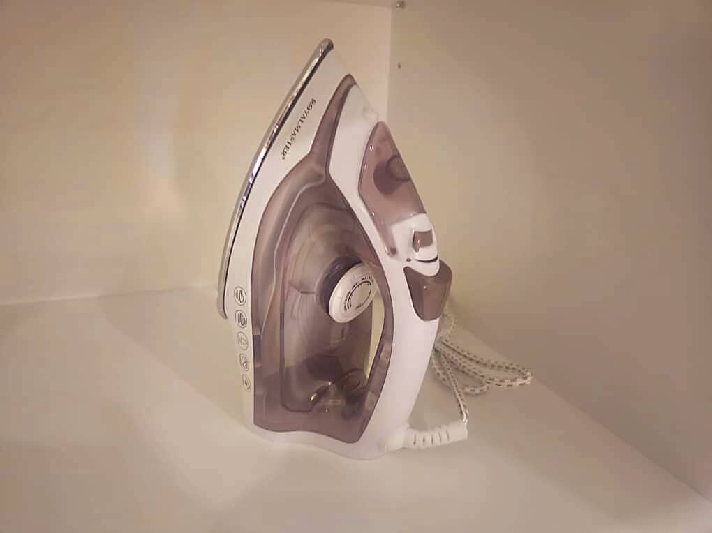 Una plancha blanca y gris con depósito de agua transparente, un cable y un panel de control.