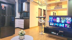 A modern living room with a flat-screen TV, a round table with a vase, a kitchen area, and a dining area. - Landmark Residence I Kajang I City View (Kajang)
