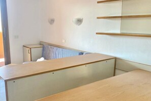 A room with a wooden desk, a bed with striped bedding, and a wall-mounted shelf. - P. Rotondo 1 I234 SEA VIEW Studio (Porto Rotondo)