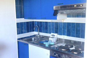 A kitchen with blue cabinets, a stainless steel sink, and a stove. - P. Rotondo 1 I234 SEA VIEW Studio (Porto Rotondo)