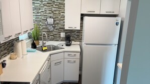A modern kitchen with white cabinets, a built-in oven, a double-door refrigerator, and a patterned backsplash.