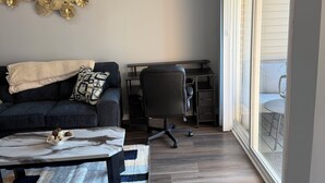 A modern living room with a sofa, coffee table, and a desk with a chair.