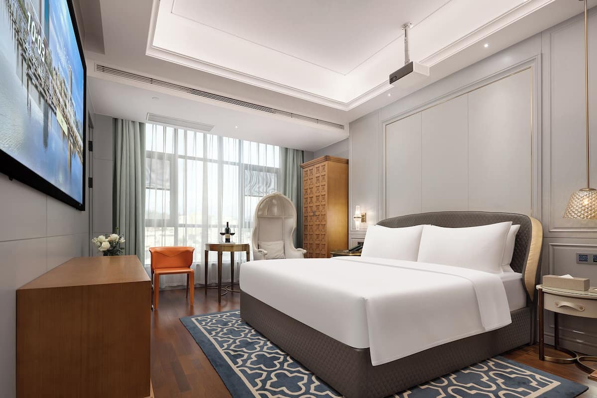 Ein Hotelzimmer mit einem großen Bett, einem Schreibtisch, einem Stuhl, einem Kleiderschrank und einem Fernseher.