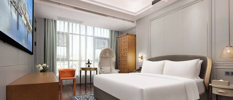 A hotel room with a large bed, a desk, a chair, a wardrobe, and a TV screen.