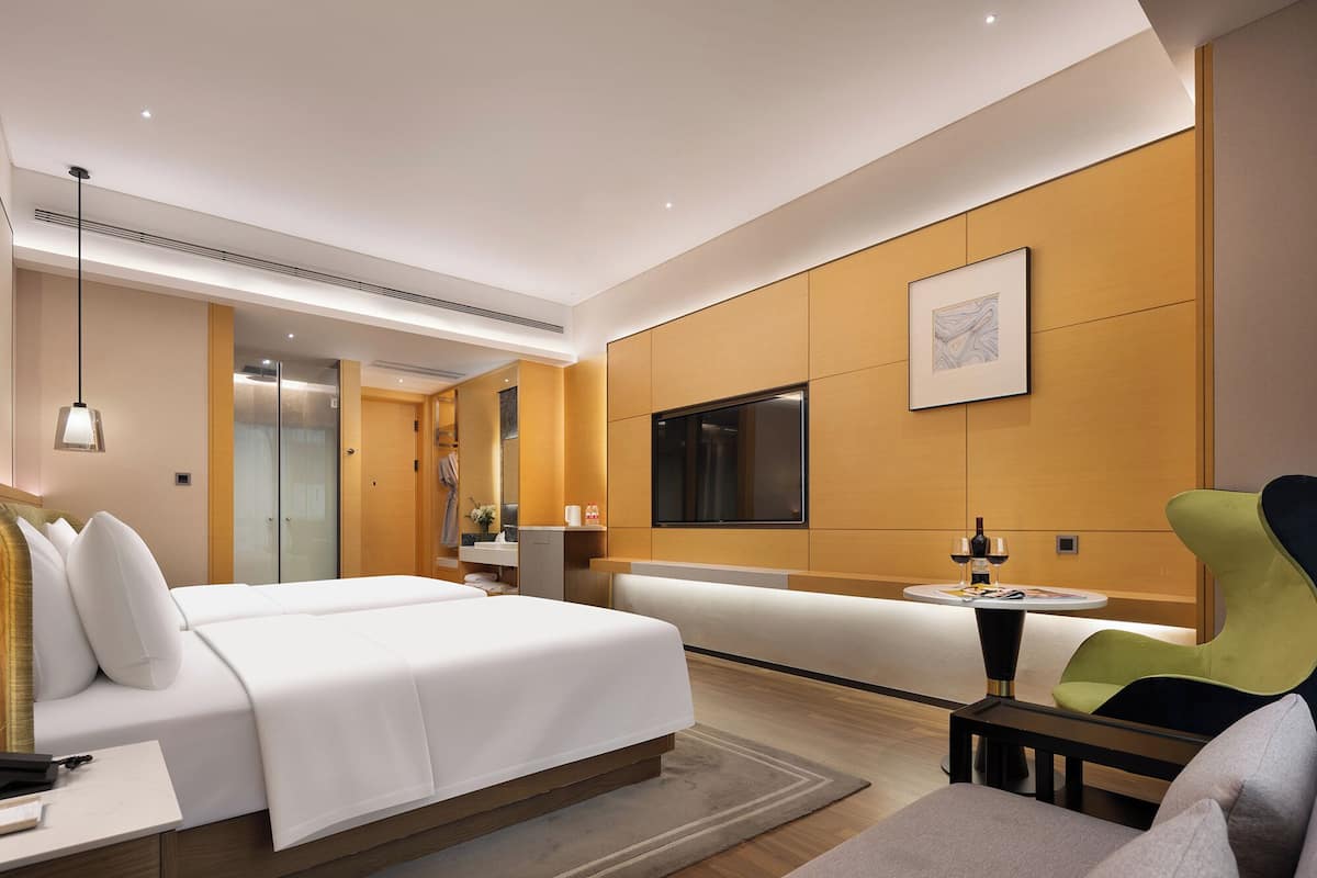 Ein modernes Hotelzimmer mit Bett, Sitzecke, Fernseher und Badezimmer.