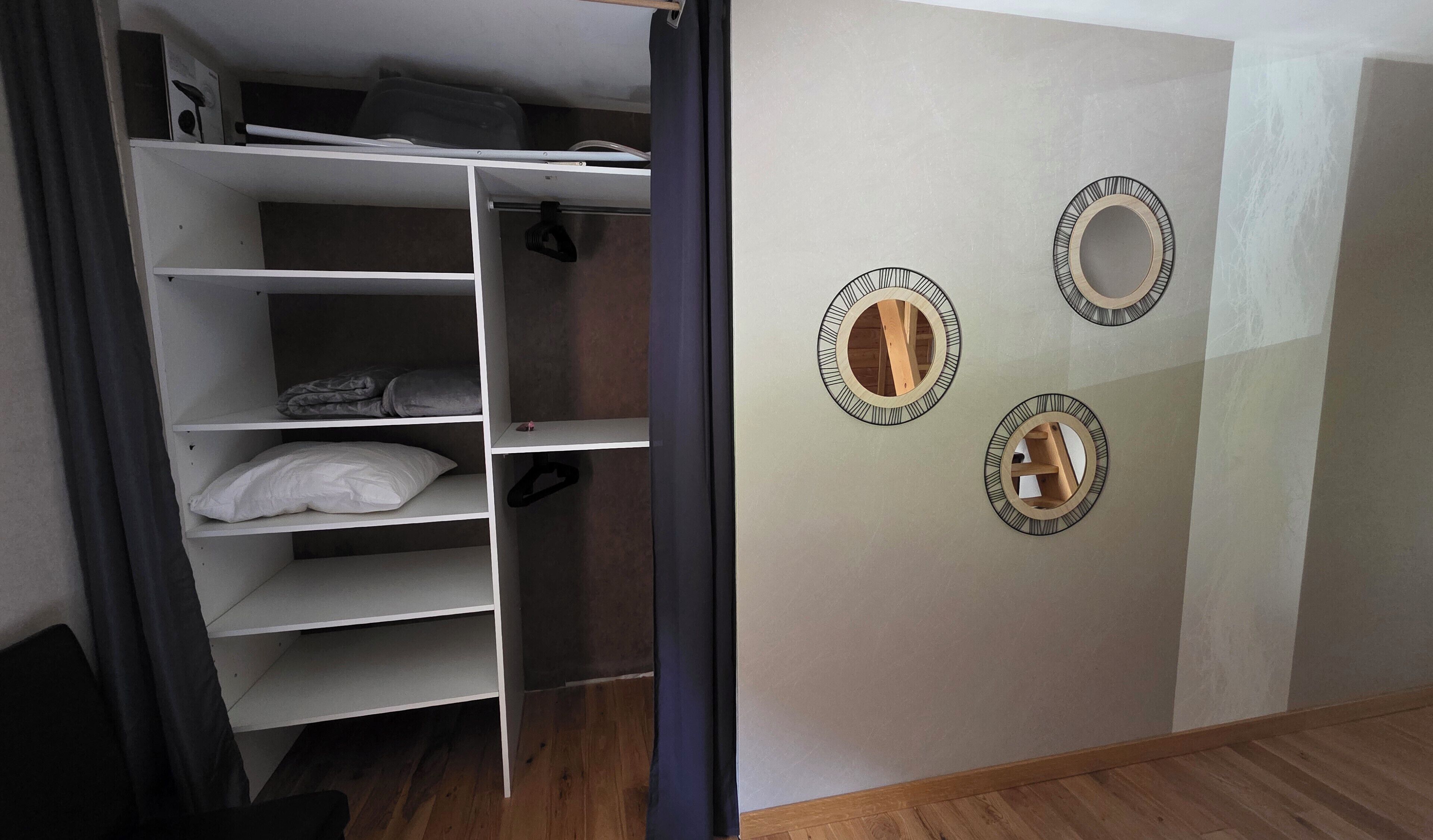 Een kamer met een kledingkast, drie spiegelwanden en een gedeeltelijk open deur.