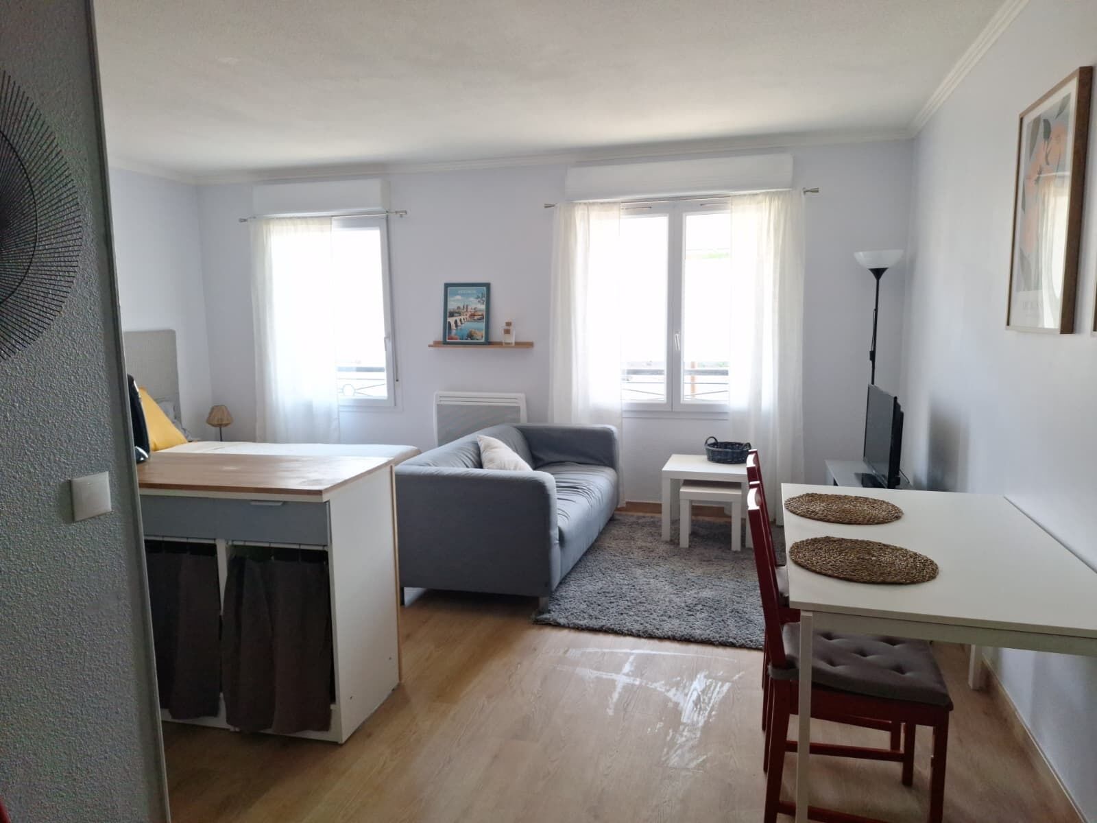 A compact living space with a bed, sofa, dining table, and a TV.