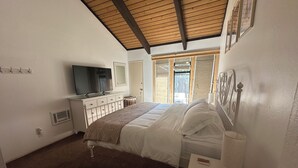 A bedroom with a bed, a TV, a dresser, a mirror, and a window with a view. - Bike, Hike & Unwind. Heated Pool, Hot Tub and Sauna. (Mammoth Lakes)