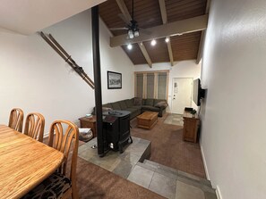Ein Wohnzimmer mit Kamin, einer Couch, einem Esstisch mit Stühlen und einem Deckenventilator.