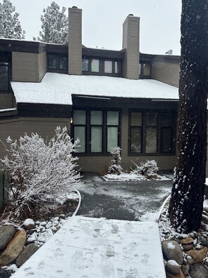 Ein Haus mit schneebedecktem Dach, einer gepflasterten Auffahrt und einer mit Schnee bedeckten Rasenfläche.