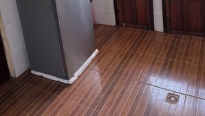 A kitchen with a refrigerator, microwave, sink, and wooden cabinets.