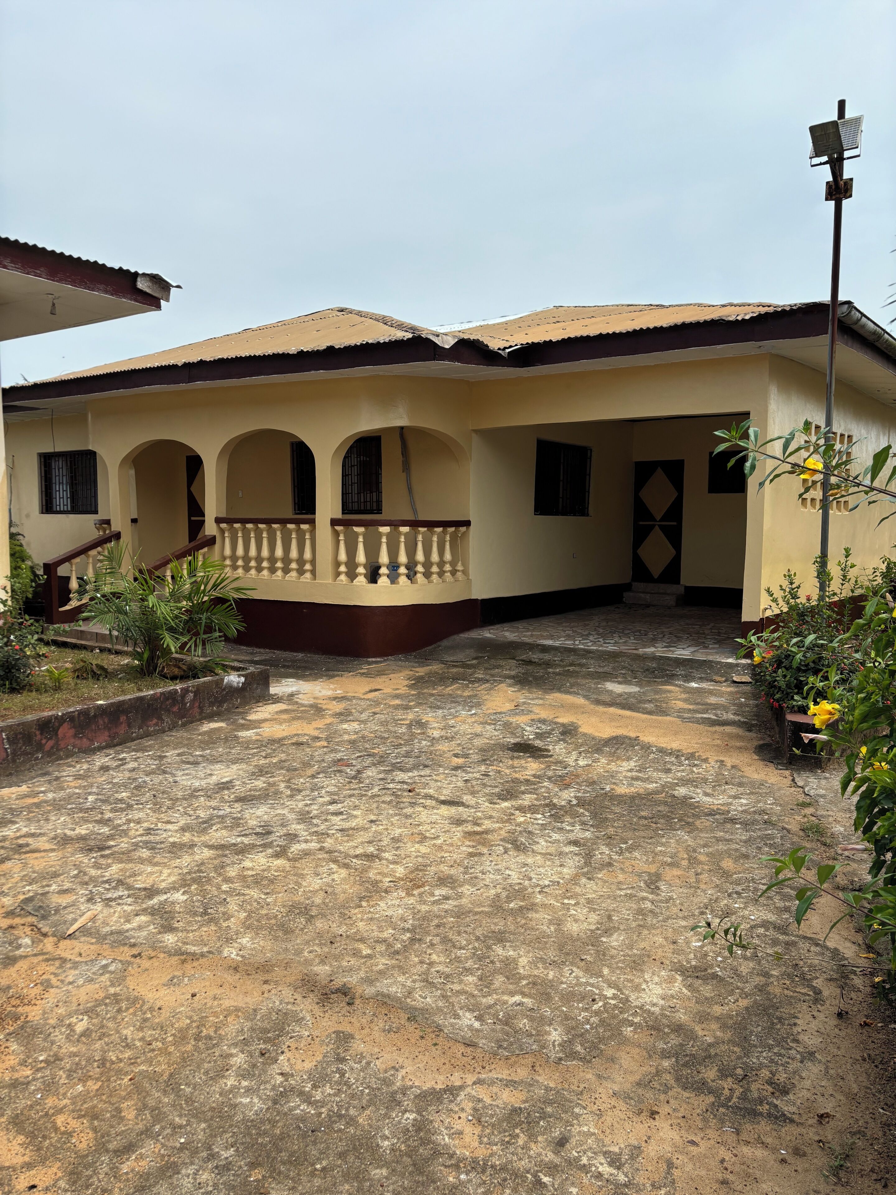 A house with a balcony, a covered entrance, and a garden area.