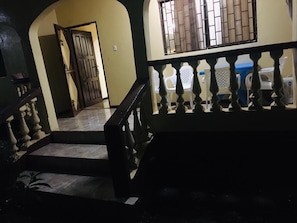 A staircase with a balustrade leading to a door, a window with bars, and a tiled floor.