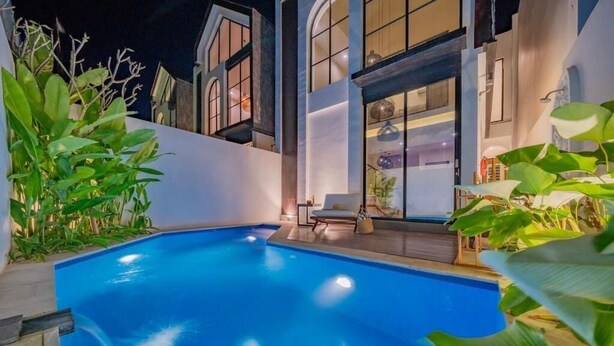 A swimming pool with a chair and a table, surrounded by plants. - 8035Coco Villa 2 Cemagi (badung)