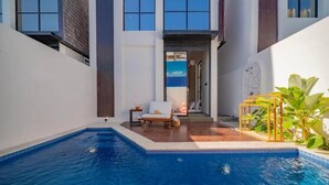 A modern pool area with a lounge chair, a small table, and a plant. - 8035Coco Villa 2 Cemagi (badung)
