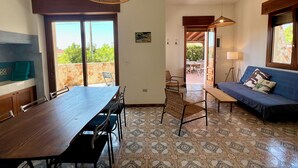 A room with a dining table, chairs, a sofa, and a patterned floor. - Villa Adua | Blueapulia (Torre Suda)