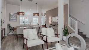 A modern kitchen with a dining area, a staircase, and a large mirror. - Family Resort Pool Home Near Disney (Kissimmee)